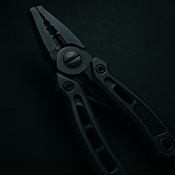 Мультитул и тонкий шнур на столике у воды в ночи