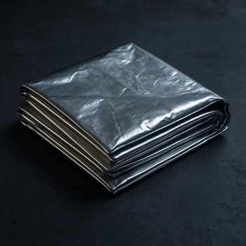 Сложенное термоодеяло и тёплые носки на сиденье у костра