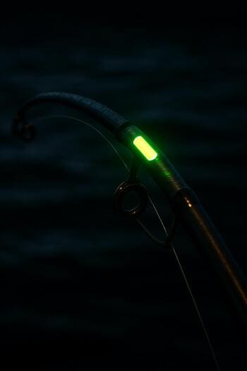 Светящаяся вершинка удилища на фоне тёмной воды