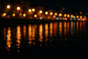 Отражения городских фонарей в ночной воде рядом с набережной