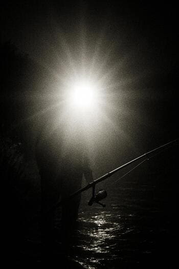 Рыболов с слишком ярким фонарём, освещающим воду